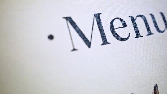 Close up of the word menu written on a textured surface in elegant serif font with a dot.