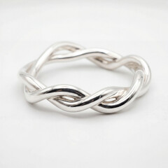 Fototapeta premium Twisted Silver Bangle on White Background with Sculptural Form for Elegant Jewelry Product Displays