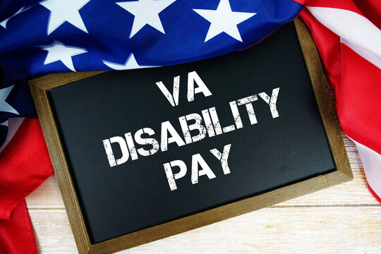 American flag with blackboard  "VA Disability Pay" on wooden background