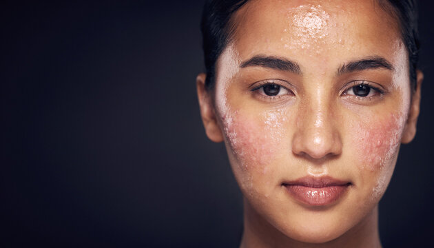 Close-up of a young woman's face with sweaty and flushed skin against a dark background, suggesting exertion or heat.