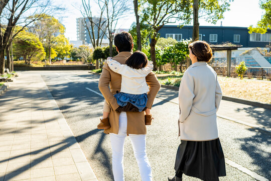 Young Japanese Family with Child on a Piggyback Ride Walking Through a Sunny Park
