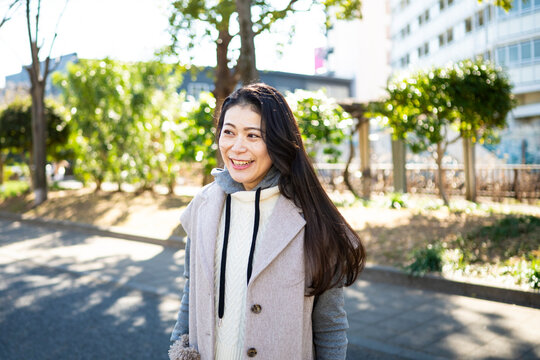 Cheerful Japanese Woman with Long Hair Smiling Brightly in Sunny Outdoor Setting