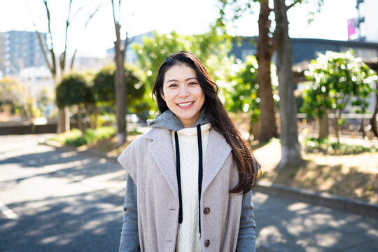 Portrait of a Smiling Mature Japanese Woman Wearing Trendy Layered Outfit in a Park