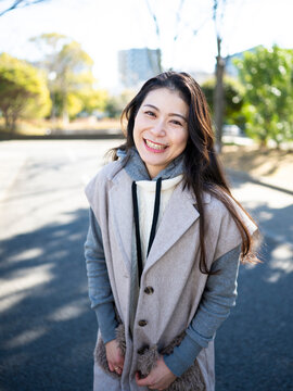 Portrait of a Smiling Mature Japanese Woman Wearing Trendy Layered Outfit in a Park