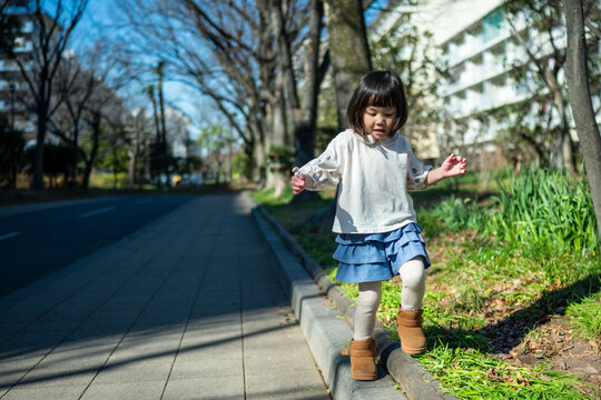 Cute Japanese little girl standing and smiling in a sunny park landscape