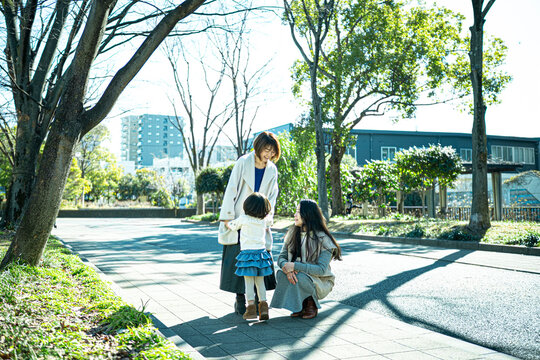 Two Japanese women and a little girl talking and laughing in a sunny urban park