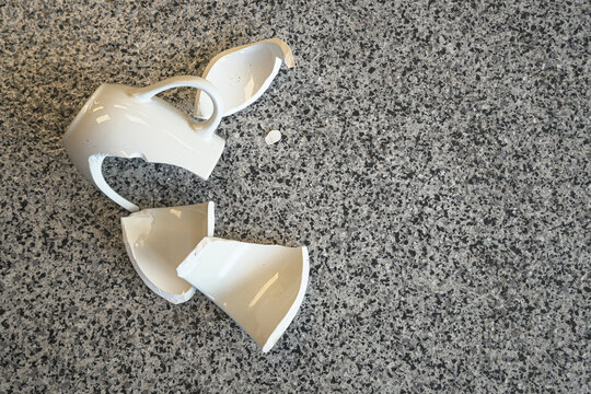 Smashed broken chinaware teacup pieces on floor