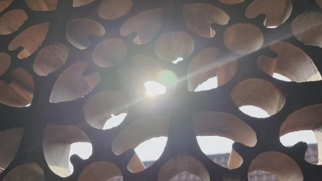 Warm Sun Lens Flare Through Traditional Perforated Terracotta Lattice Architectural Screen
