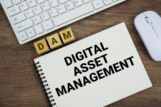 DAM Digital Asset Management message with keyboard and optical mouse on wooden background