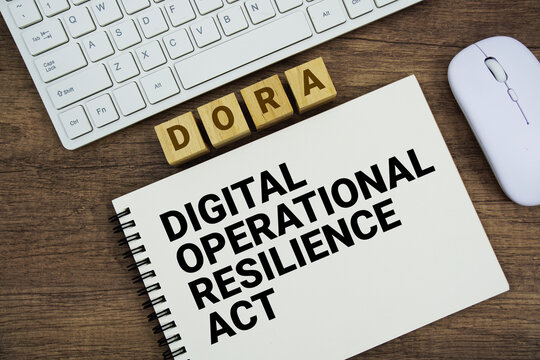 DORA Digital Operational Resilience Act message with keyboard and optical mouse on wooden background