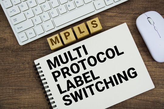 MPLS Multiprotocol Label Switching message with keyboard and optical mouse on wooden background