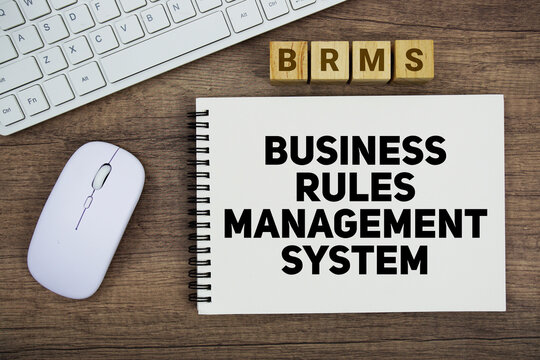 BRMS Business Rules Management System message with keyboard and optical mouse on wooden background