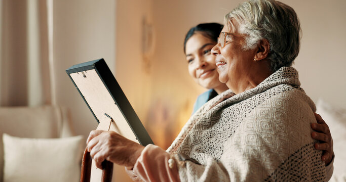Happy, daughter and old woman in home with picture frame, family memories or love for bonding together. Senior mother, smile and people in lounge with photograph, nostalgia and remember past history.