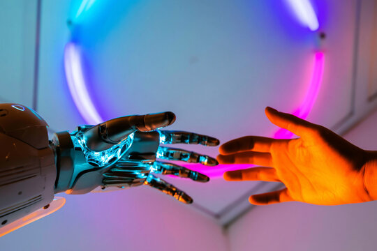 A robotic hand and a human hand reaching out to each other in a futuristic setting with neon lights