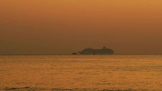 Cruise ship overtaking fishing boat in sunset time.