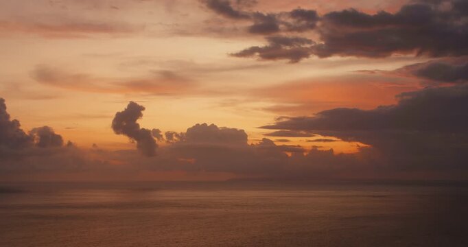 Sunset light glows through heavy clouds above the Indian Ocean at twilight
