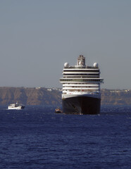 Luxury classic cruiseship cruise ship liner Eurodam anchoring at sea on sunny summer day during Mediterranean Greek Island Santorini caldera cruising with shore and rocky island in background © Tamme Wichmann