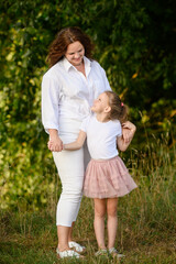 Fototapeta premium Happy mature mother and daughter spending time together standing in summer park looking at each other and hugging. Concept of late parenthood, nature recreation, love. Mother-daughter relationship