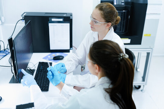 Team of female scientists analyzing digital pathology slides on computer. Caucasian and Asian researchers reviewing histology data for medical diagnosis in modern lab.