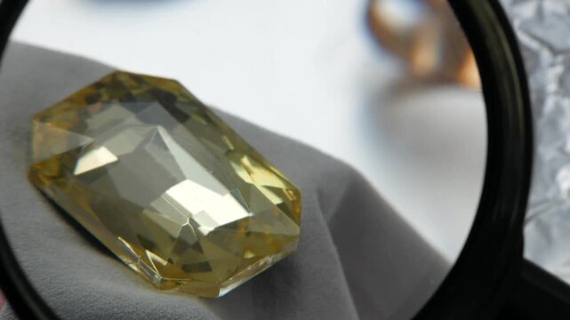 Gemologist jeweler evaluates the value and purity of yellow stones at a pawn shop.