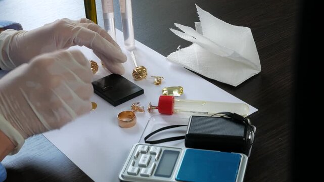 Pawnshop worker verify golden jewelry on many golden and silver jewelleries, scales and money background. Customers Buy and Sell Precious