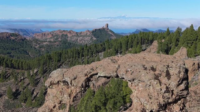Astonishing aerial shot slowly revealing the Roque Nublo monolith and Mount Teide volcano through a natural rock arch in Gran Canaria (Ga&ntilde;ifa).