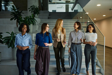 Fototapeta premium Diverse businesswomen walking, talking, and smiling in office building