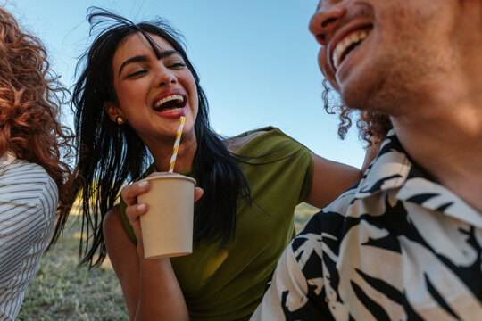 Happy friends laughing and drinking outdoors together