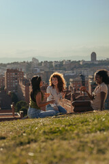 Multicultural female friends enjoying picnic with pizza at city park