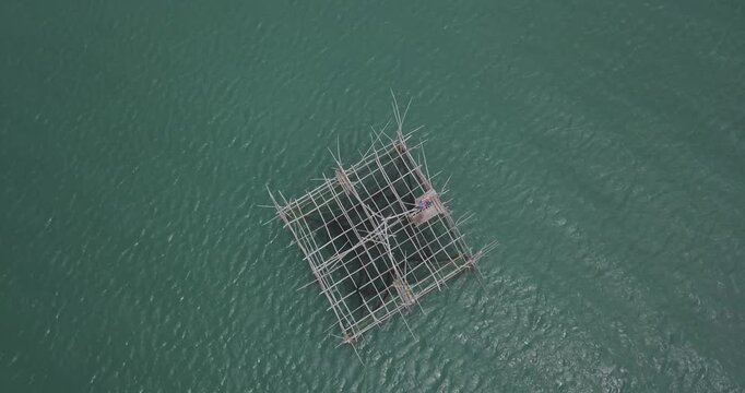 Aerial top down drone shot rotating over traditional bamboo fishing platform surrounded by clear tropical water in Guimaras Philippines