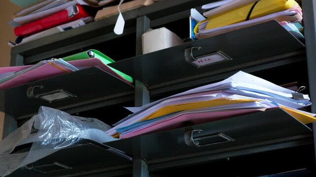 Stacks of paper files and folders cluttered on metal shelves in a poorly maintained medical facility in Cameroon. Close-up view.