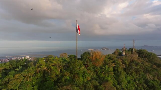 Aerial drone shot of Ancon Hill and the Panama flag as it ascends and reveals the Amador Causeway