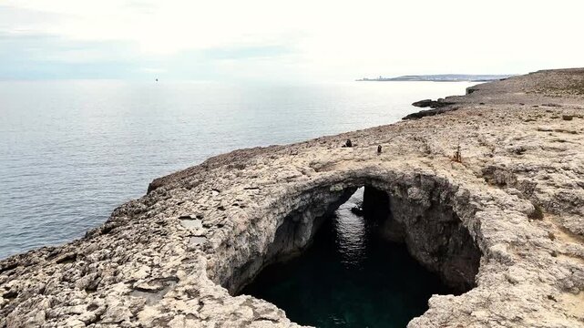 Coral Lagoon Il-Qarraba in Mellieħa Malta shows elliptical collapse doline formed from coastal sea cave within Upper Coralline Limestone plateau connected to Mediterranean via tunnel near Armier bay