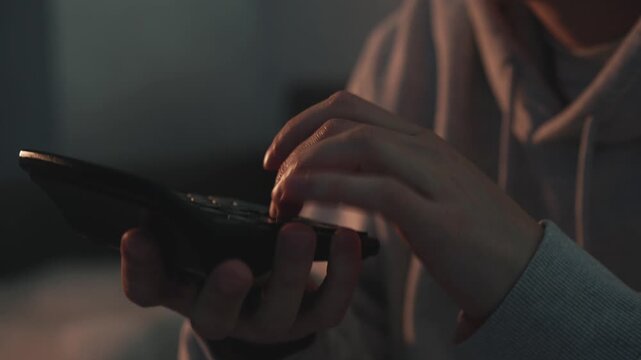 Close-up of hands of a financial professional using a calculator to process numbers in a dark office environment. Concept of business planning, financial management, and economic decision making.