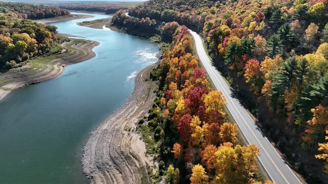 Aerial view of a scenic road winding along a river in autumn.