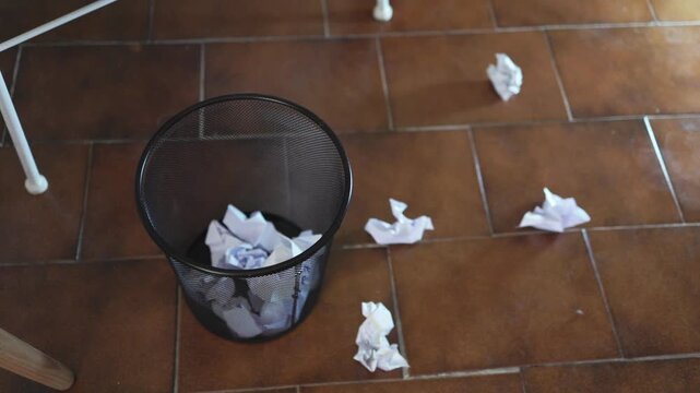 Throwing crumpled paper balls into a trash can