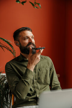 Man with beard sending voice message using smartphone