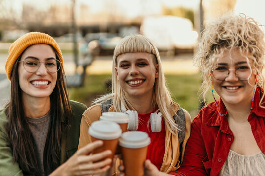Generation z women friends toasting coffee outdoors