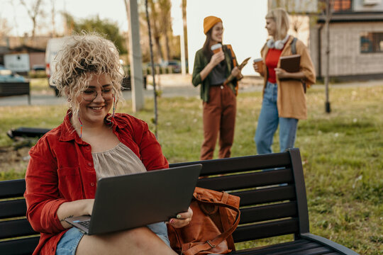 Happy student using laptop enjoying campus park
