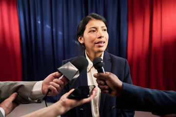 Medium shot of Latin young adult politician answering reporters during press conference, addressing...