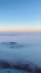 Fototapeta premium Mountain peaks emerging through a sea of clouds under a clear sky.