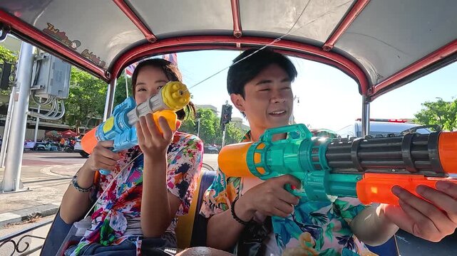 Young Asian Couple Celebrating Songkran Festival with Water Guns in Tuk Tuk