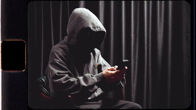 Anonymous hooded person using a smartphone