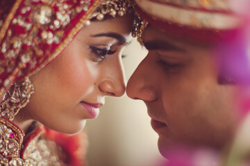 Obraz premium Close-up portrait of indian bride and groom with soft romantic expressions and wedding decorations blurred in background, ultra-sharp focus