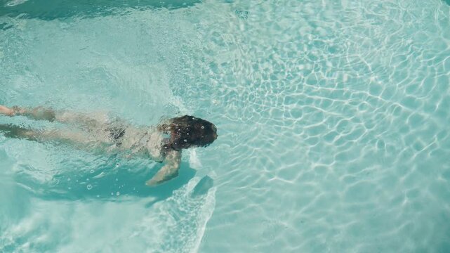 Woman in bikini swimming underwater in pool