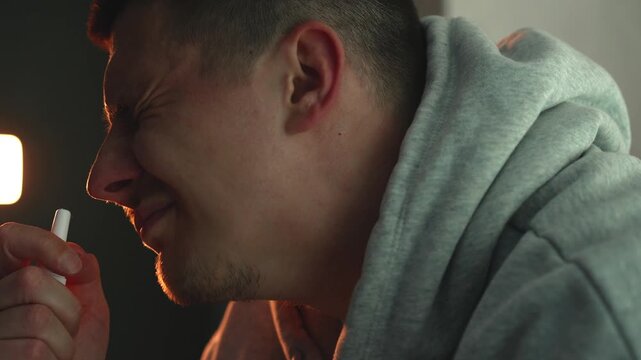 Close-up of a person treating blocked nose with nasal spray at night. Focus on respiratory health, allergy or cold symptoms, sinus relief, and medication use in a home environment