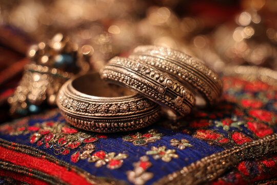Traditional rajasthani silver anklets and jewelry displayed on embroidered textile in jaipur market, soft warm lighting