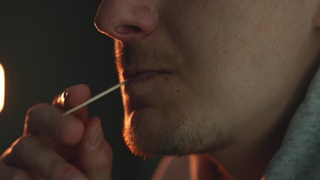 Close-up of person cleaning teeth with wooden toothpick after dinner at home. Oral hygiene, dental care, removing food particles, healthy routine, prevention of dental problems, everyday lifestyle con