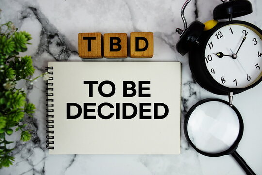 TBD To Be Decided text with alarm clock and magnifying glass on marble background