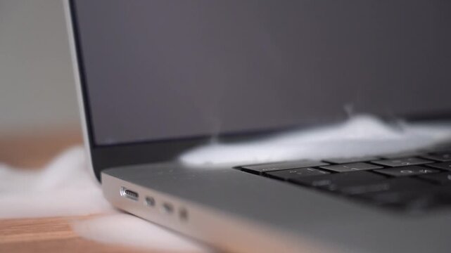 The laptop starts to smoke. The beginning of ignition from the laptop. The laptop has overheated and is igniting. High quality FullHD footage